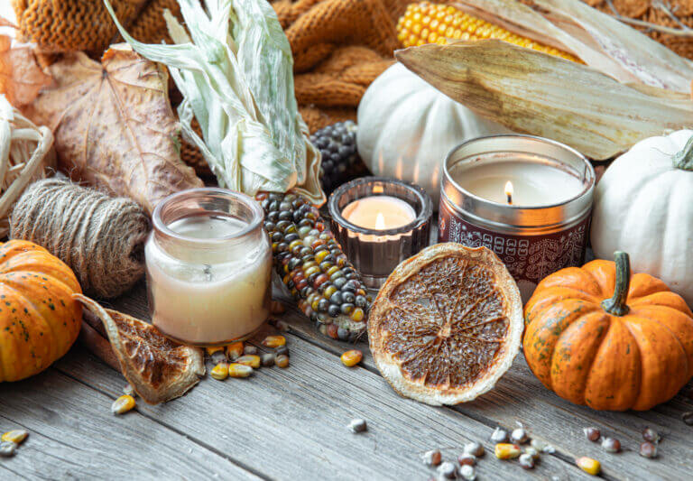 Scents of the Season: September Autumn background with candles, pumpkins, corn and knitted element.